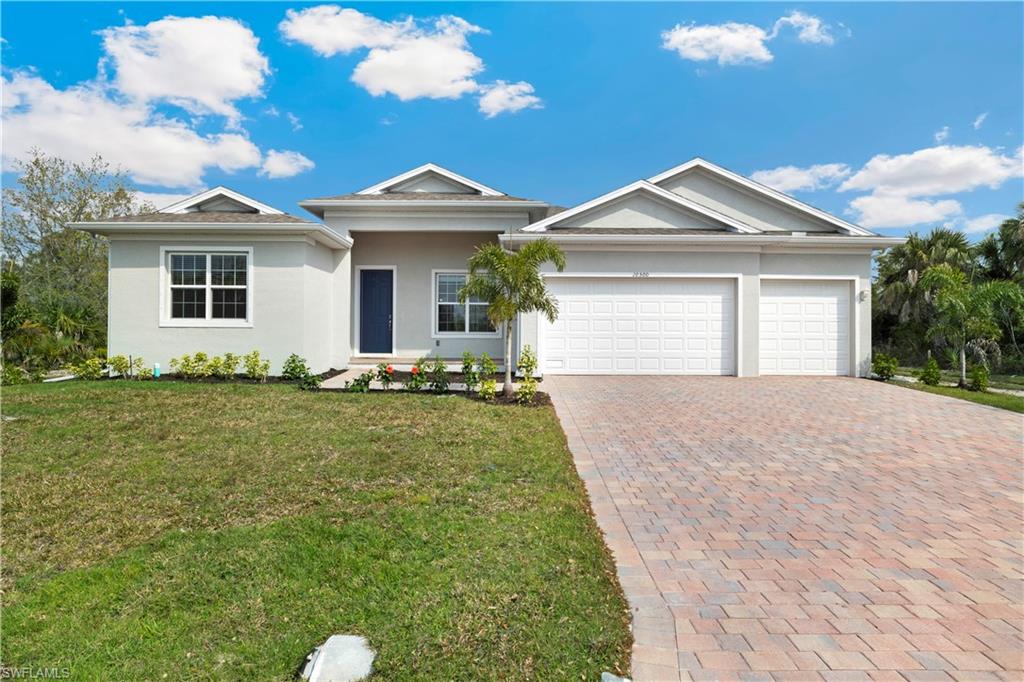 MODEL HOME - Contemporary stucco exterior featuring a two-car garage, paver driveway, and a deep blue entry door