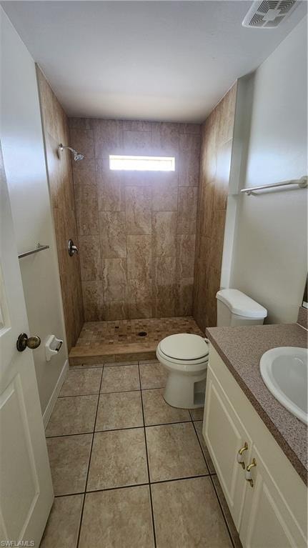 Bathroom featuring a tiled walk-in shower with a transom window, a vanity with a solid surface countertop, an undermount sink, and tiled flooring