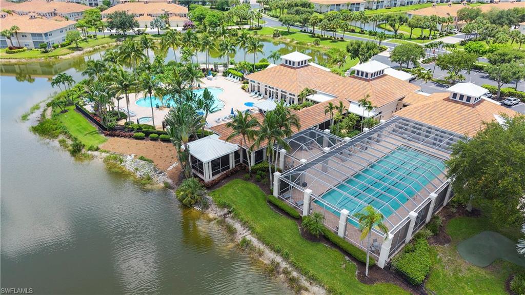 Community amenity center featuring two swimming pools, one screened and one open-air, surrounded by lush landscaping and palm trees
