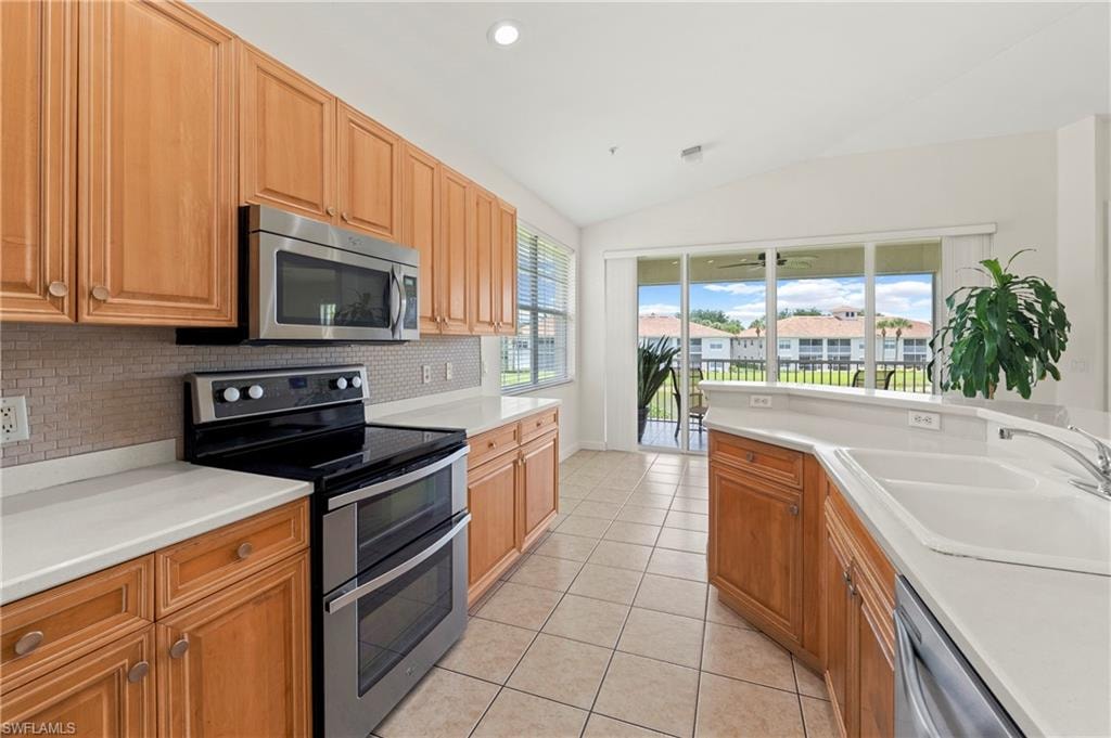 Kitchen featuring wood cabinetry, stainless steel appliances, light-toned countertops, and a tiled backsplash