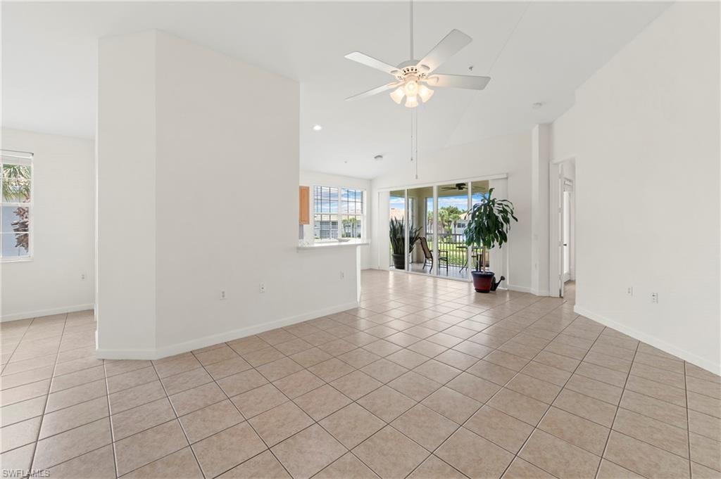 Spacious interior with tile flooring throughout, featuring a vaulted ceiling and a ceiling fan