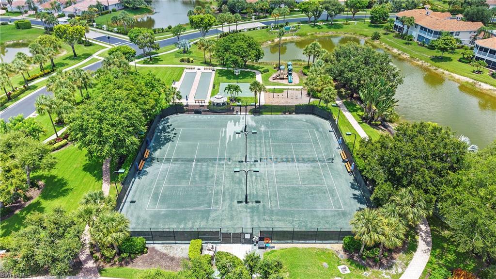 Community recreational amenities featuring two tennis courts with lighting, a bocce ball court, a covered gazebo, and a children's play structure, all surrounded by mature landscaping