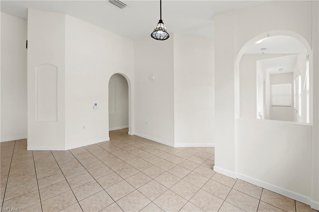 Spacious interior featuring neutral tile flooring, high ceilings, and arched doorways