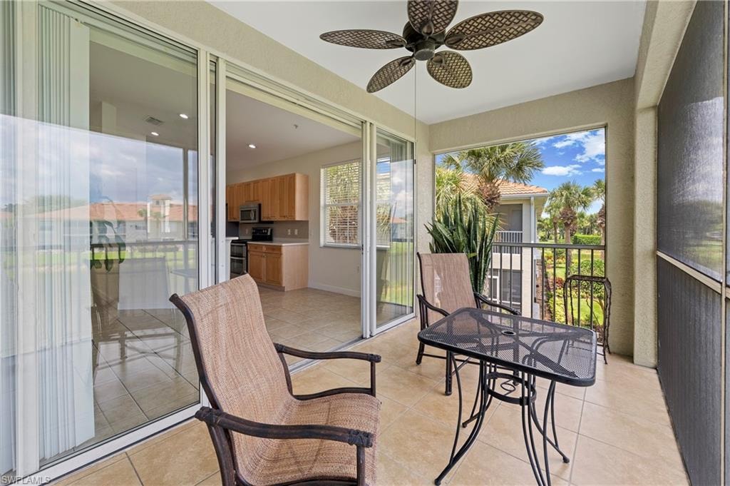 Screened balcony with tile flooring, ceiling fan, and sliding glass door access to the interior