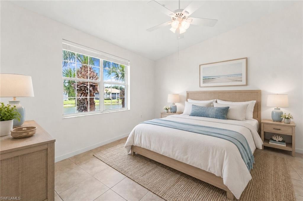 Vaulted ceiling bedroom featuring a large window with water and tropical foliage beyond