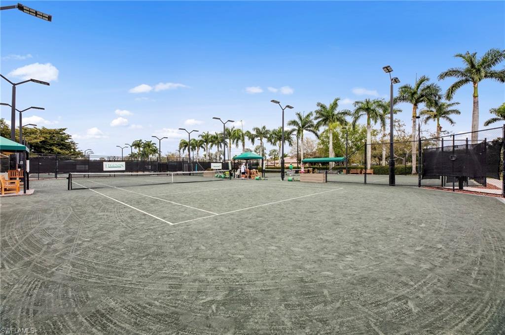 Regulation-size tennis courts with perimeter fencing and dedicated lighting structures