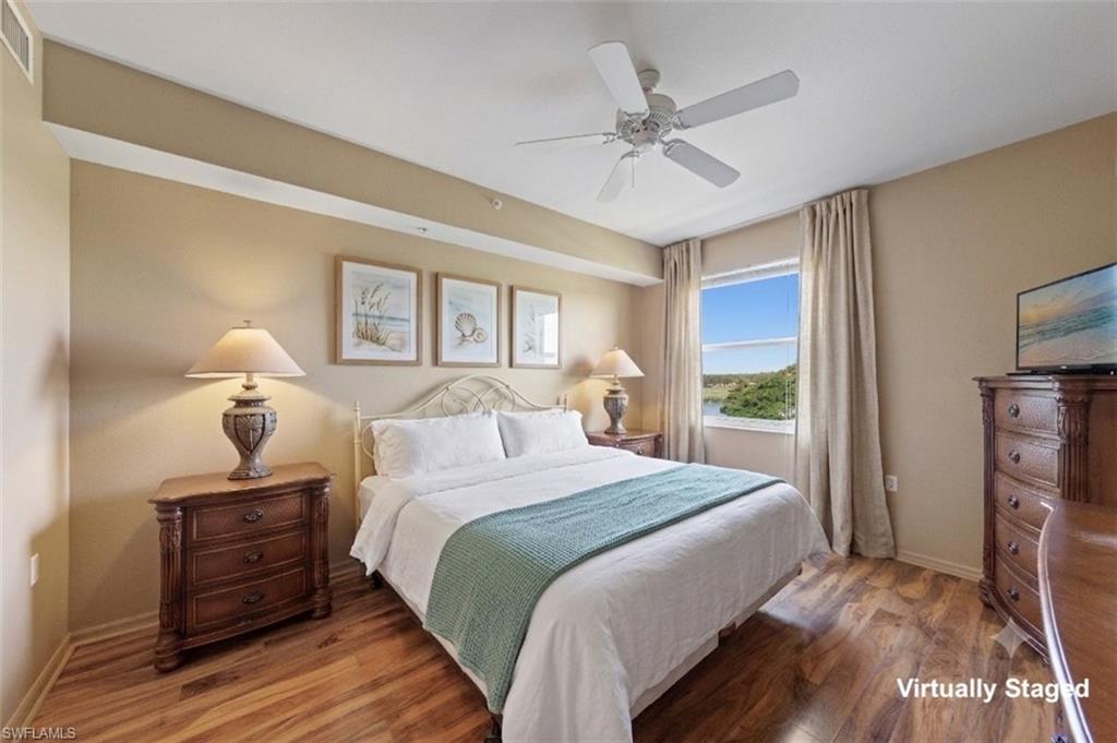 Bedroom featuring wood-finish flooring, a ceiling fan, and a window offering a distant water and tree-lined landscape