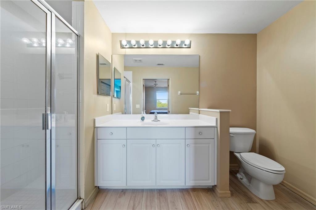 Bathroom featuring a single vanity with white cabinetry, a white countertop, and a large wall-mounted mirror