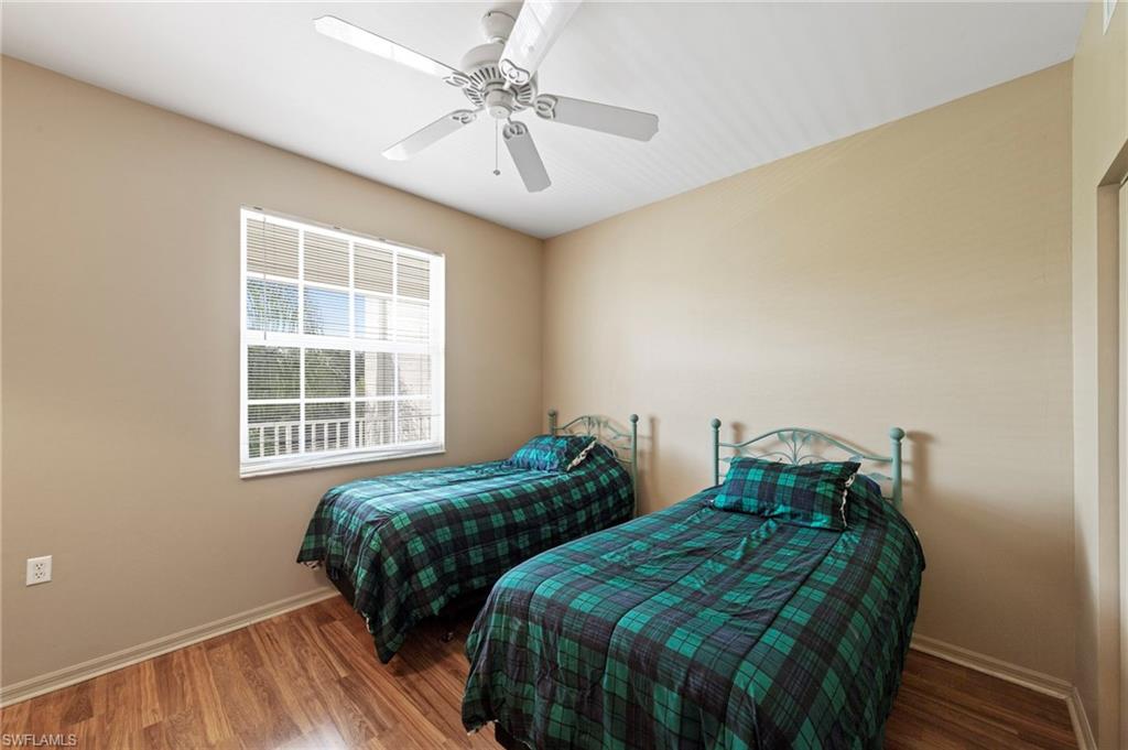 Room featuring a white-framed window with blinds, wood-finish flooring, a ceiling fan with integrated lighting, and neutral-toned wall paint