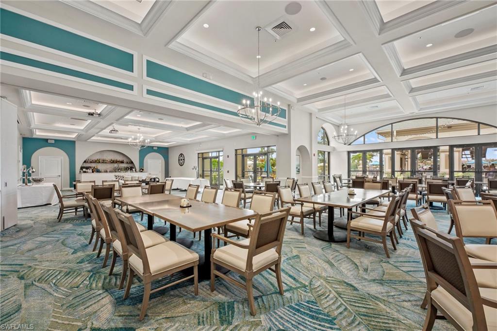 Spacious interior featuring decorative coffered ceilings with recessed lighting, a built-in bar area with arched alcove, floor-to-ceiling glass doors, and large arched windows