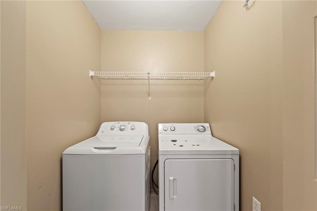 Dedicated laundry area featuring a white top-load washing machine, a white front-load dryer, and a white wire shelf