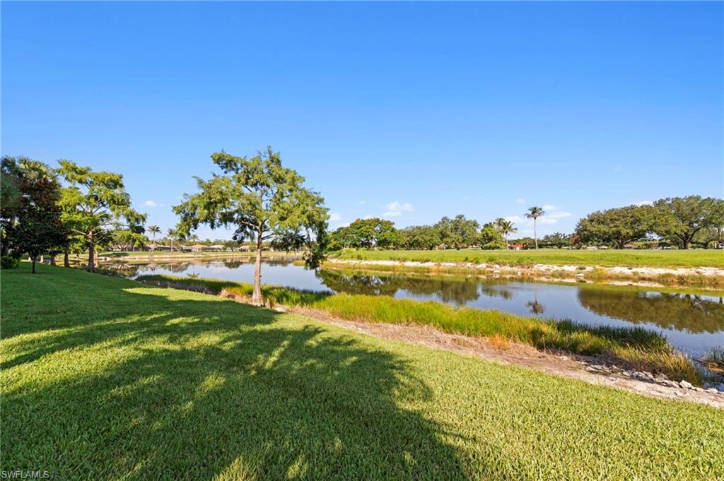 Expansive outdoor space featuring a water feature, manicured lawn, and mature trees
