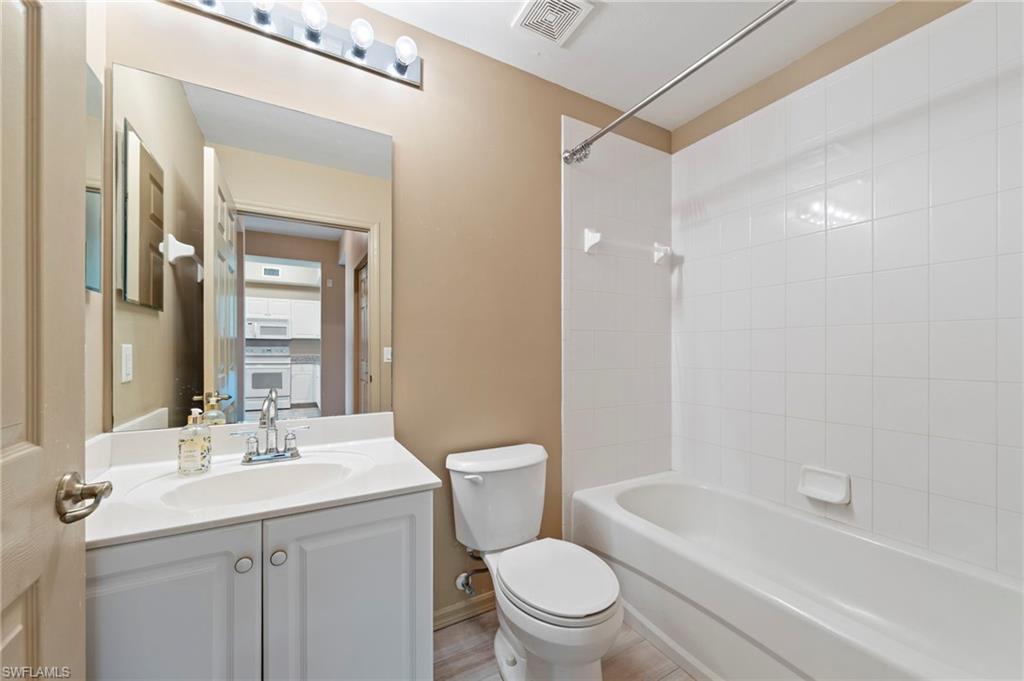 Bathroom featuring a white vanity with integrated sink, chrome faucet, and overhead bar lighting