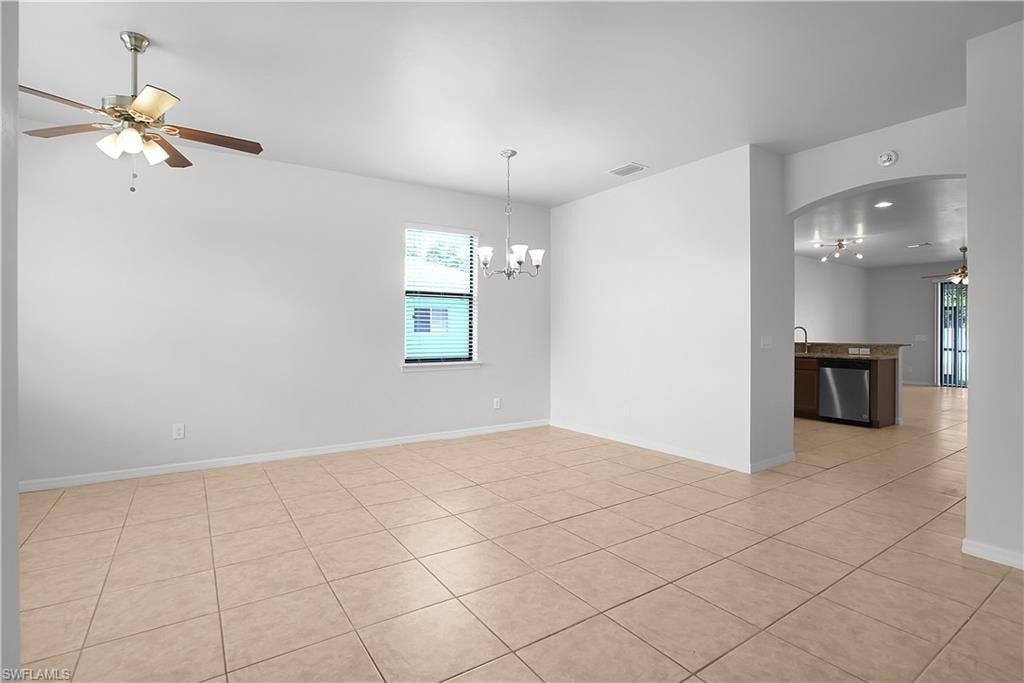 Spacious interior featuring large format tile flooring, a contemporary chandelier, and a ceiling fan with light fixture