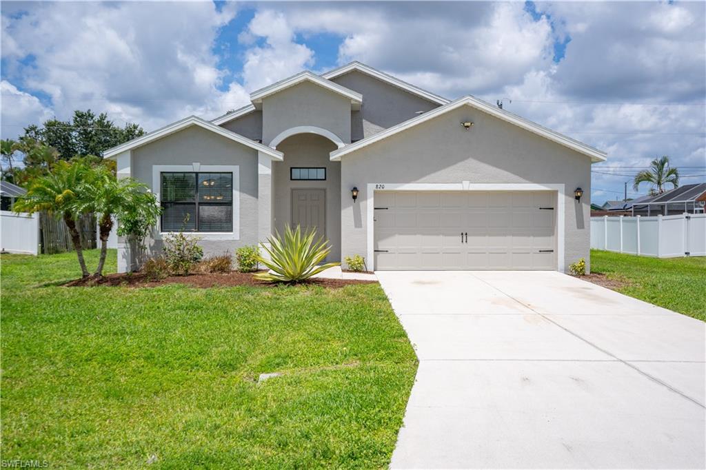 Contemporary stucco exterior with an arched entryway, integrated garage, and a concrete driveway