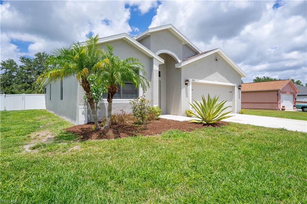 Contemporary stucco exterior featuring a two-car garage, concrete driveway, and a white privacy fence