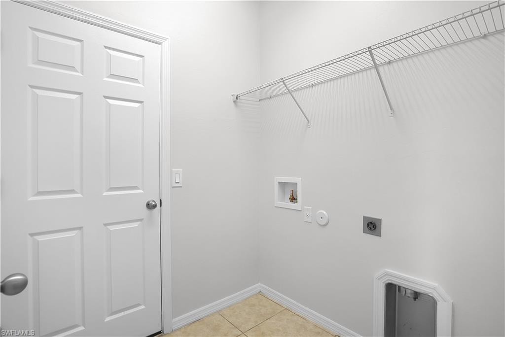 Dedicated utility space featuring tile flooring, white baseboards, and a paneled interior door