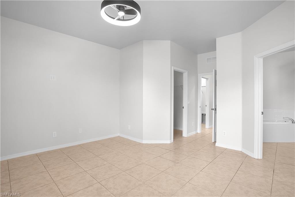 Spacious room featuring neutral-toned tile flooring, white baseboards, and a modern ceiling light fixture