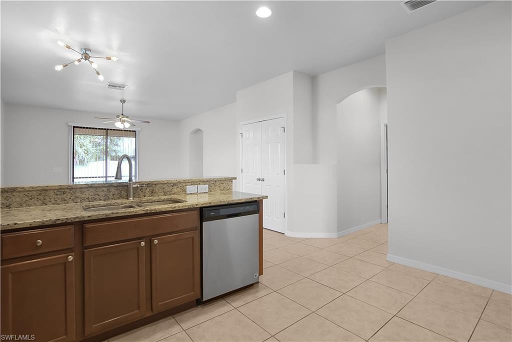 Kitchen featuring wood-finish cabinetry, stainless steel dishwasher, and a double basin sink with a gooseneck faucet