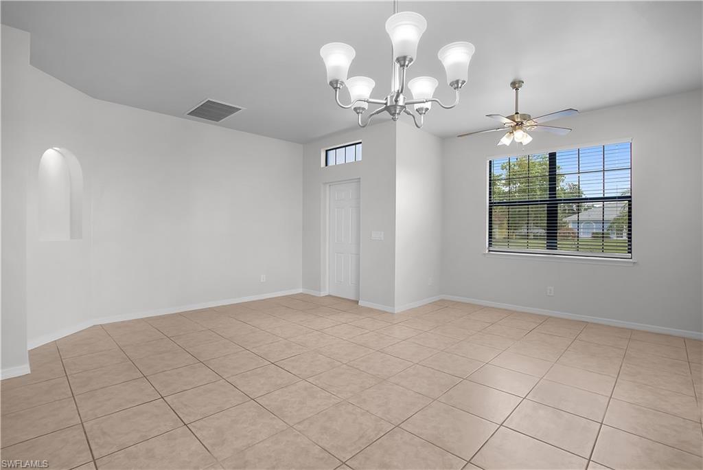 Spacious room featuring neutral tile flooring, a large window with horizontal blinds, and a decorative arched wall niche