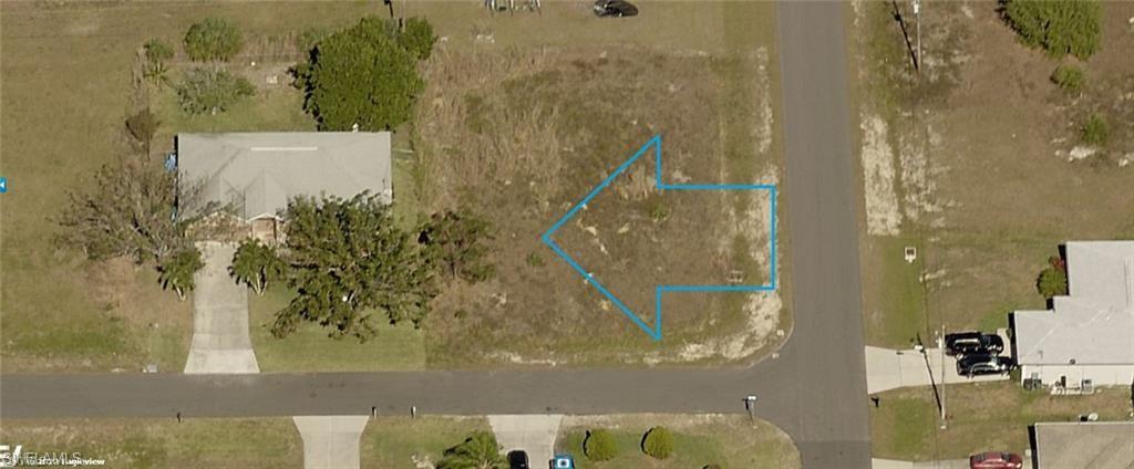 Vacant corner lot featuring a partial outline indicating property boundaries, street frontage, and surrounding undeveloped land