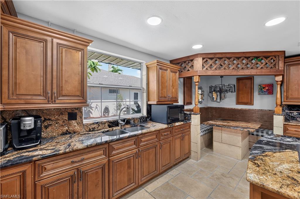 Kitchen featuring wood-finish cabinetry, granite countertops, and a built-in dining nook with decorative wood lattice work