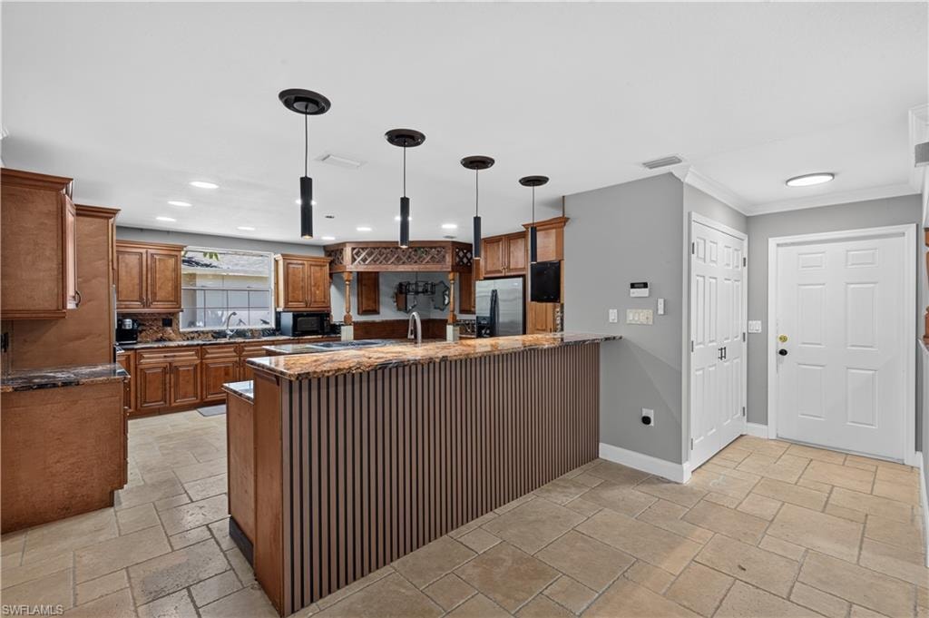 Kitchen featuring wood cabinetry, a central island with a slatted base, and a breakfast bar