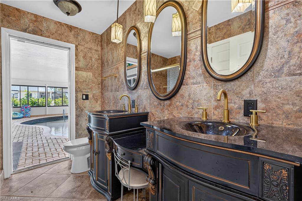 Ornate black vanity with gold hardware, oval undermount sink, and brass faucet
