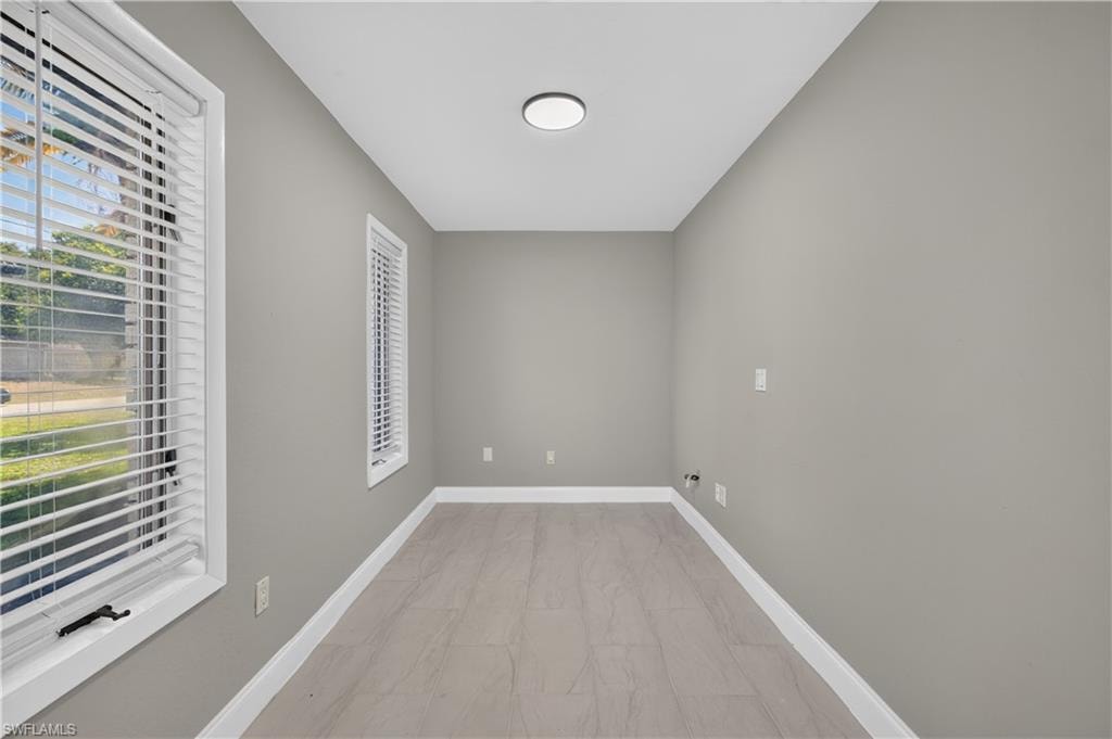 Rectangular interior space featuring light gray wall paint and contemporary wood-finish plank flooring
