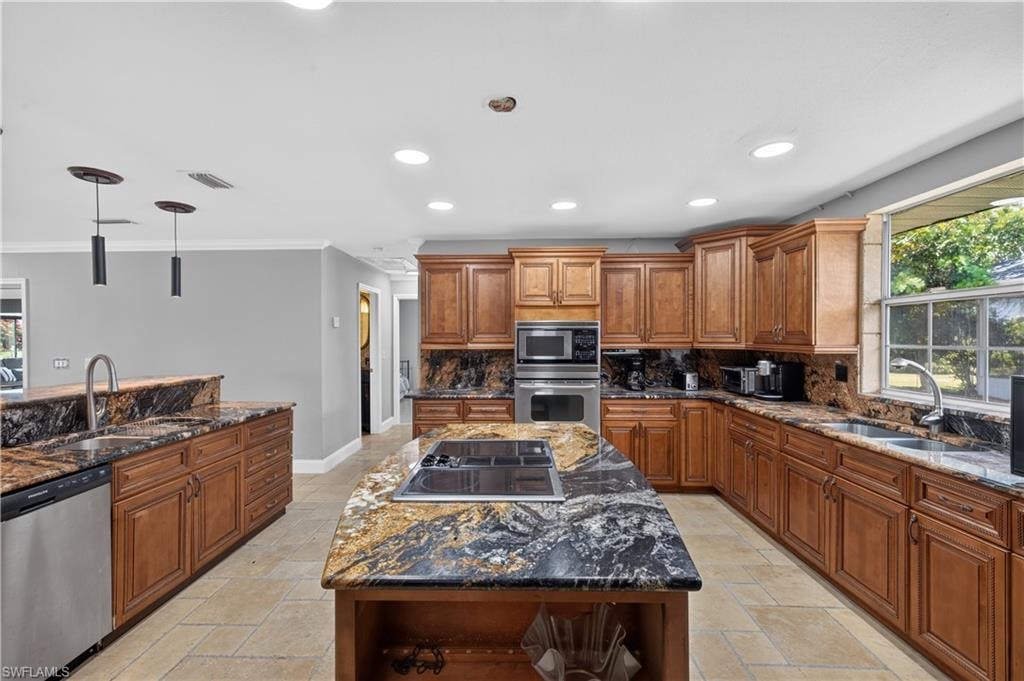 Open concept kitchen featuring wood cabinetry, integrated stainless steel appliances, a multi-tone granite island with an electric cooktop, and matching granite countertops and backsplash