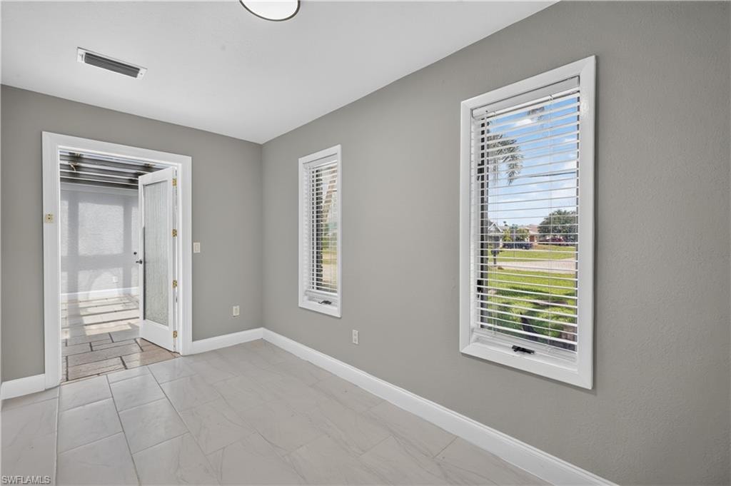 Room featuring light gray walls, white baseboards, and light-toned tile flooring