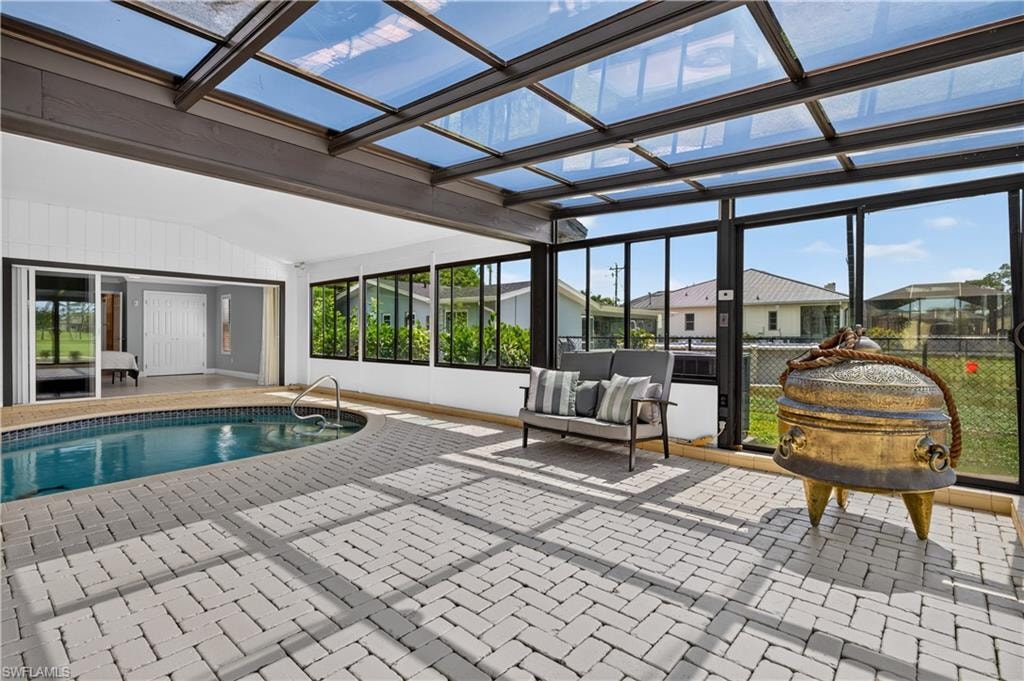 Expansive enclosed patio featuring a swimming pool, glass-paneled roof, and perimeter windows