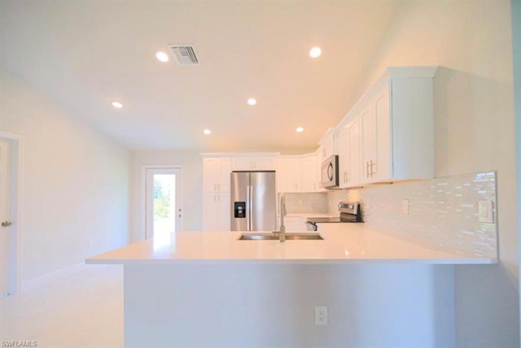 Modern kitchen featuring white cabinetry, light countertops, stainless steel appliances, a subway tile backsplash, and recessed lighting