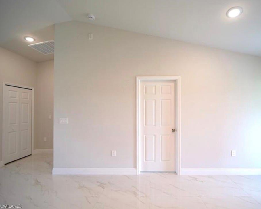 Vaulted ceiling with recessed lighting, complemented by white six-panel doors and white trim