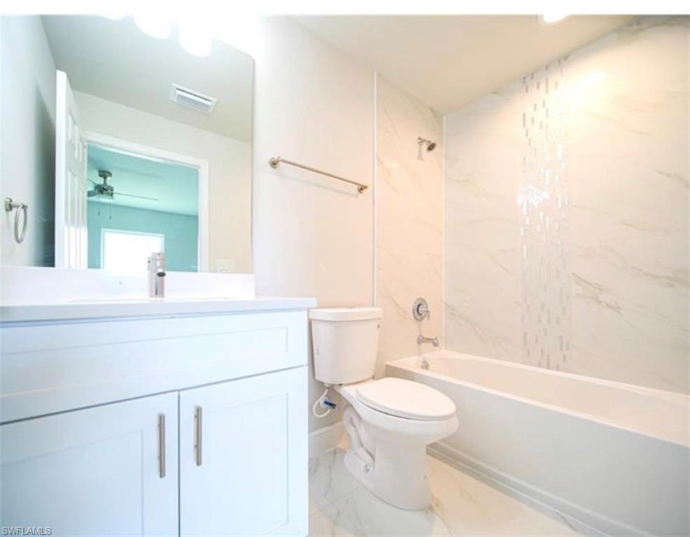 Bright bathroom featuring a white vanity with integrated sink, chrome faucet, and contemporary hardware