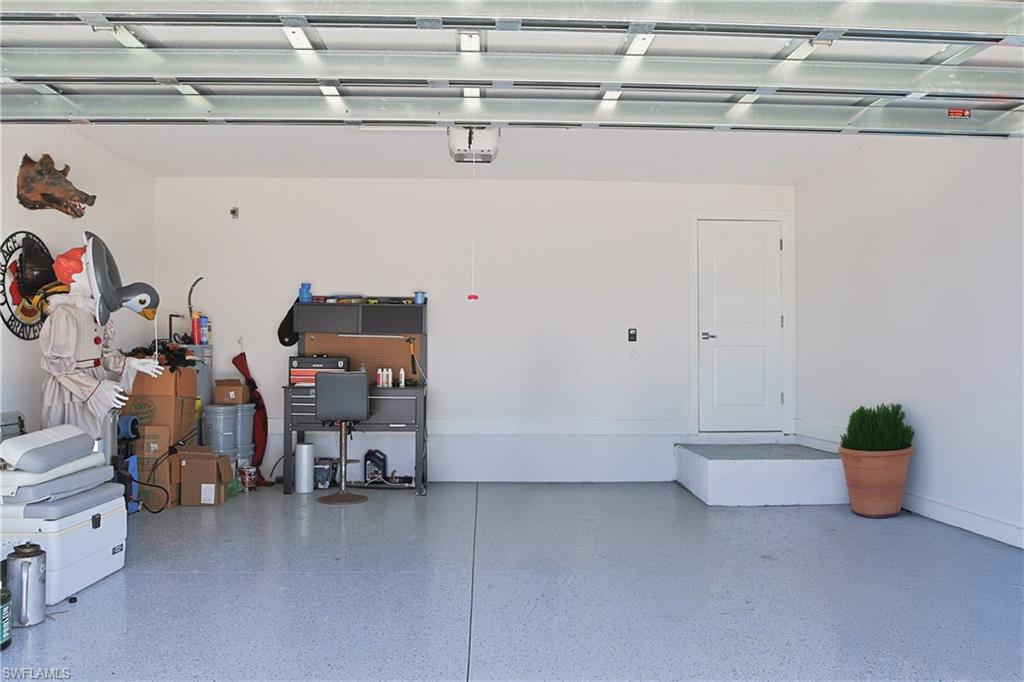 Spacious garage featuring white walls, a finished epoxy floor, and an interior access door with a white trim
