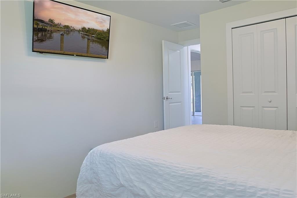 Interior room with light-toned walls, featuring a wall-mounted television, white bi-fold closet doors, and an open doorway