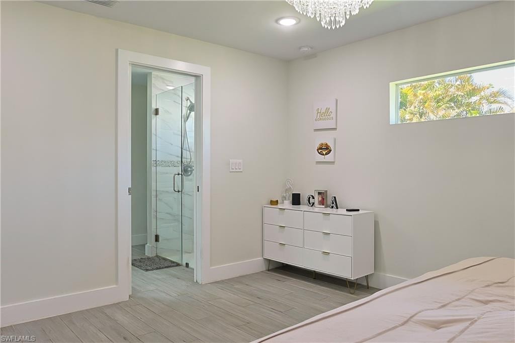 Light-toned wood-finish flooring extending from the room into a full glass-enclosed shower with tiled walls