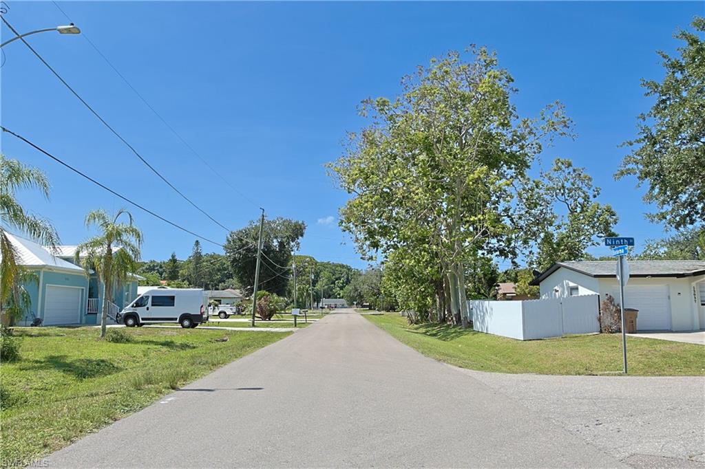 Paved street with overhead utilities, mature trees, and street signage