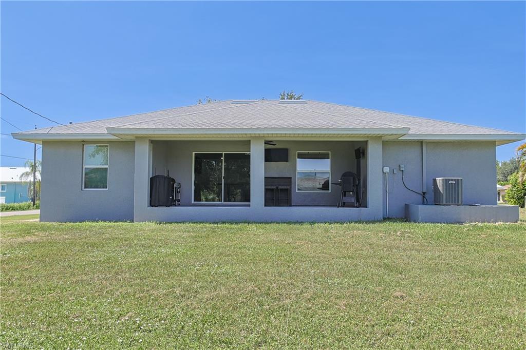 Rear exterior featuring a covered patio, sliding glass doors, multiple windows, and exterior stucco finish