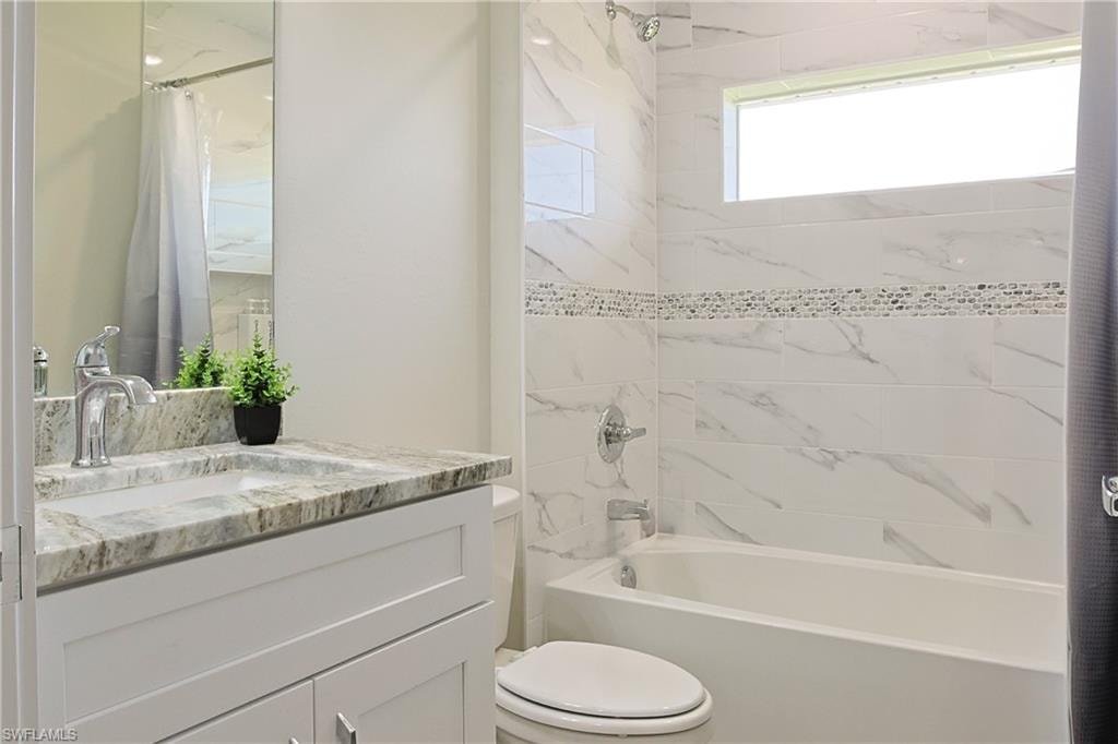 Bathroom featuring a white vanity with a light-toned stone countertop and integrated sink