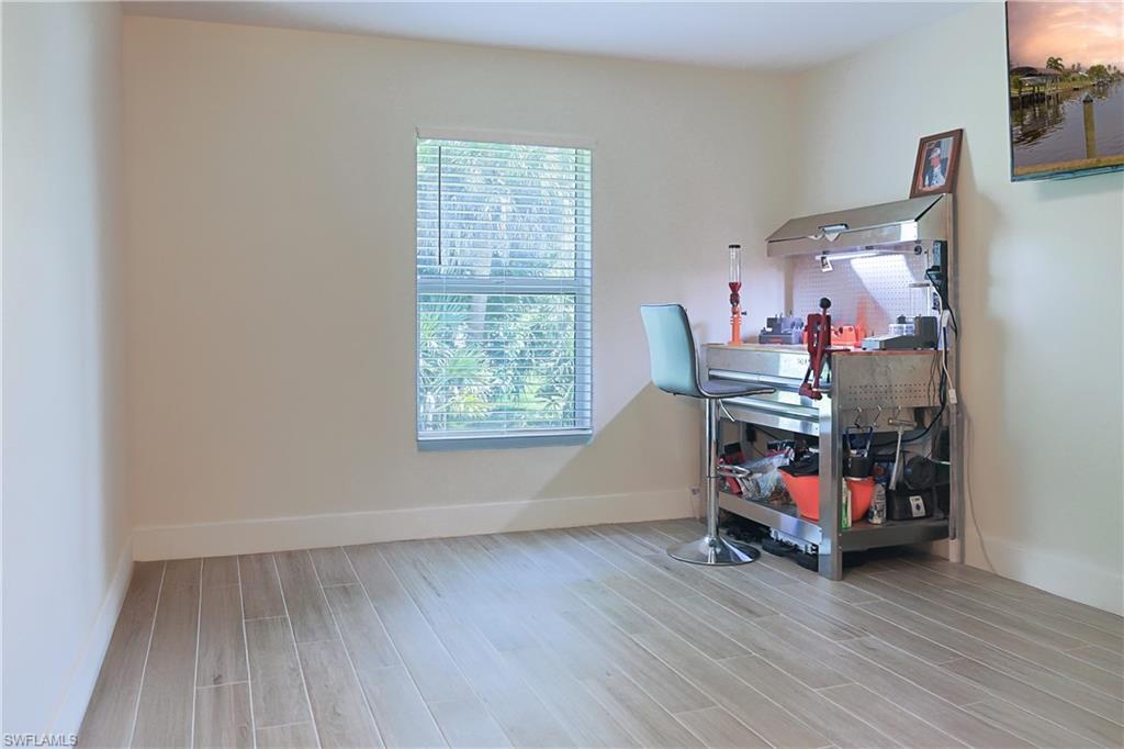 Room featuring wood-finish plank flooring, light-toned walls, and a window with horizontal blinds