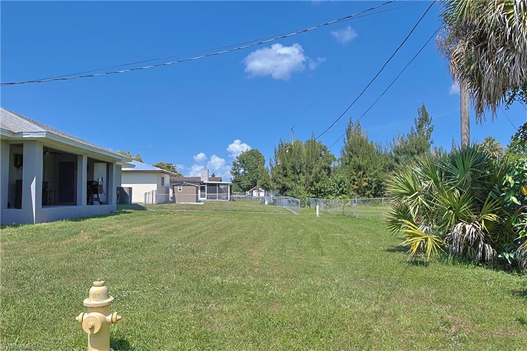 Expansive backyard featuring a lush lawn, chain-link fencing, and mature perimeter foliage