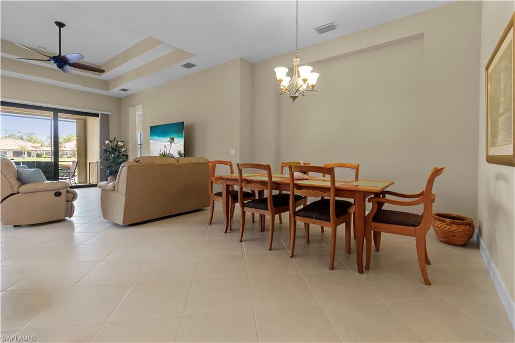 Spacious interior featuring neutral tile flooring, a tray ceiling with a ceiling fan, and sliding glass doors to the exterior