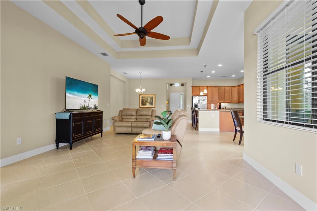 Open-concept living area featuring tile flooring, a tray ceiling with a ceiling fan, and recessed lighting