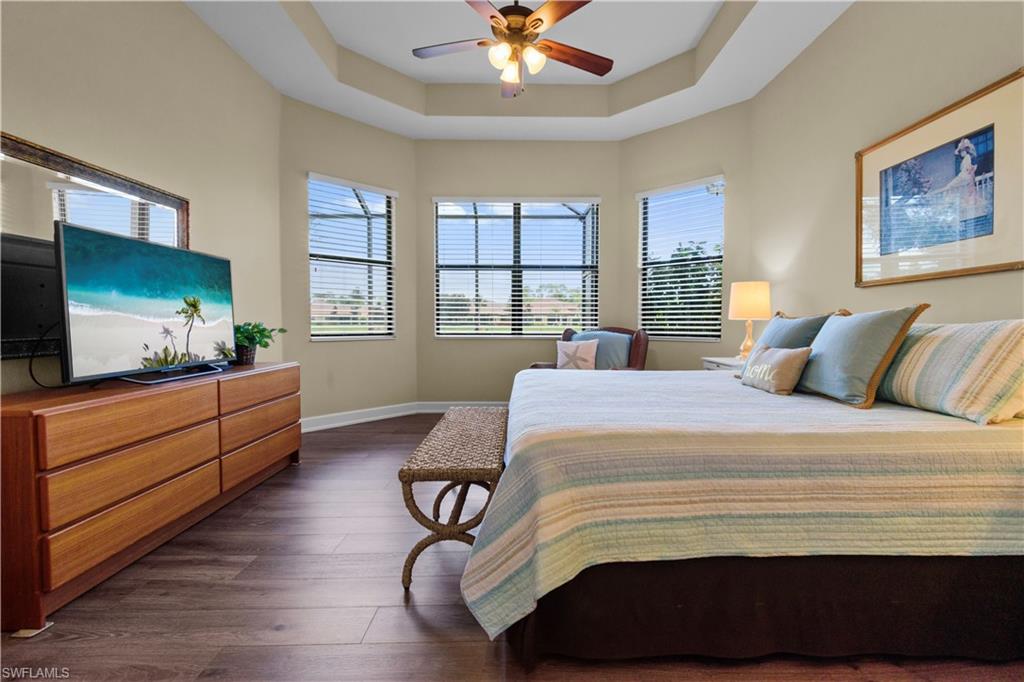 Spacious primary bedroom featuring wood-finish flooring and a tray ceiling