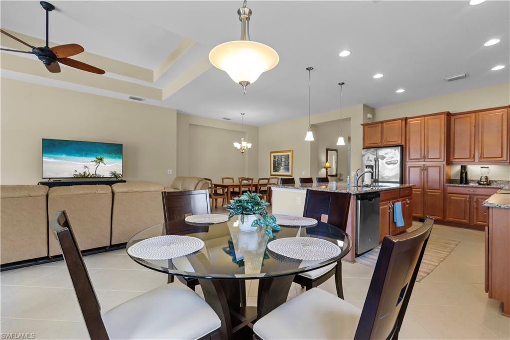 Open-concept living space featuring a kitchen with wood cabinetry, a central island with a sink, and stainless steel appliances