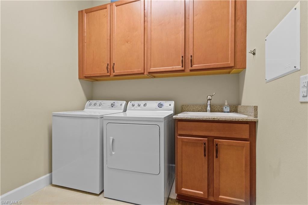 Dedicated laundry area featuring upper and lower wood-finish cabinetry, a utility sink with a stone-finish countertop, and a single-handle faucet