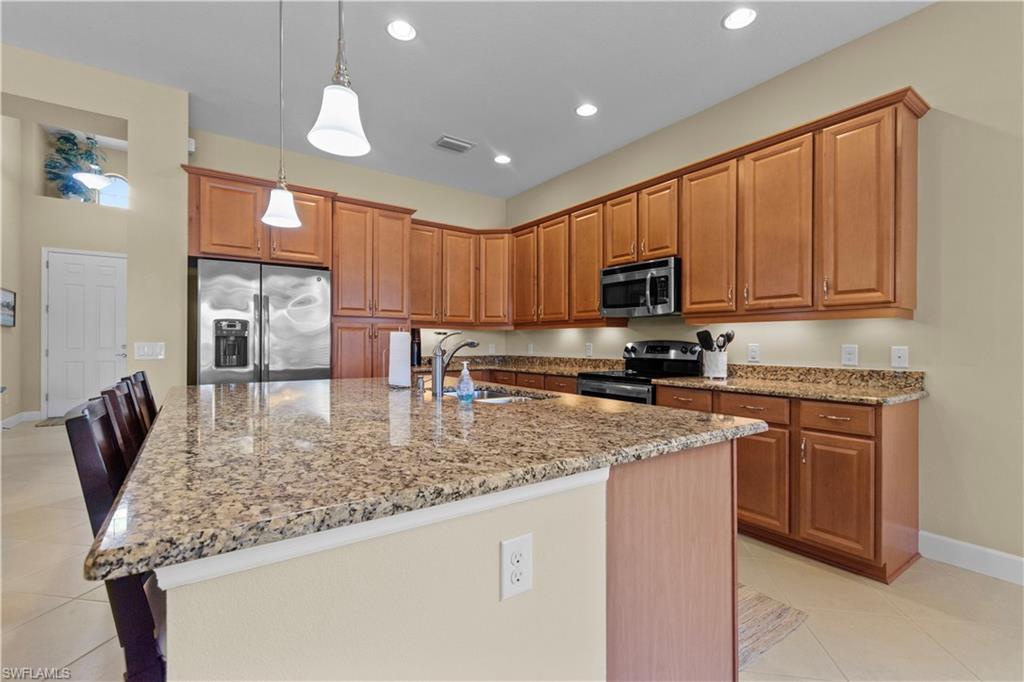 Spacious kitchen featuring a large island with stone countertops, stainless steel appliances, abundant cabinetry, and recessed lighting