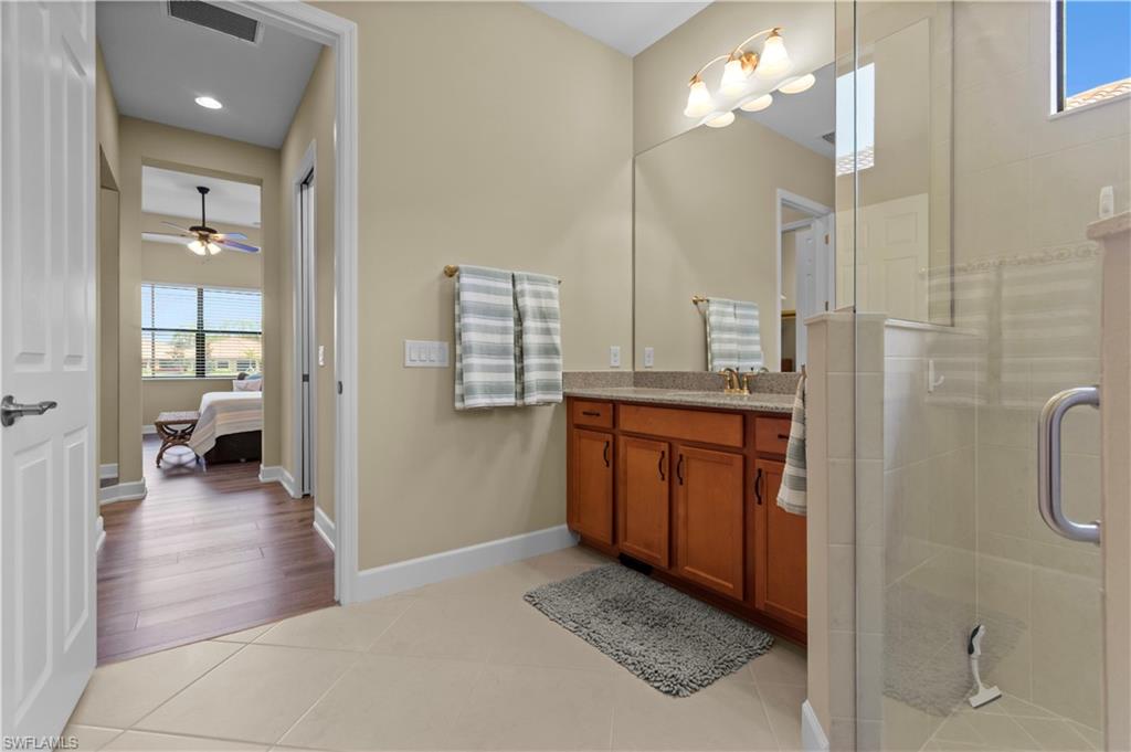 Bathroom vanity featuring a light-toned countertop, wood-finish cabinetry, and a large wall-mounted mirror